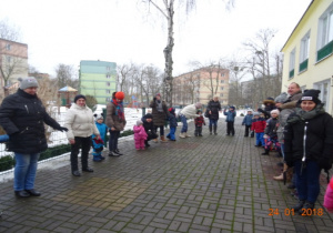 Dzieci i rodzice stoją w kole na tarasie przedszkolnym.
